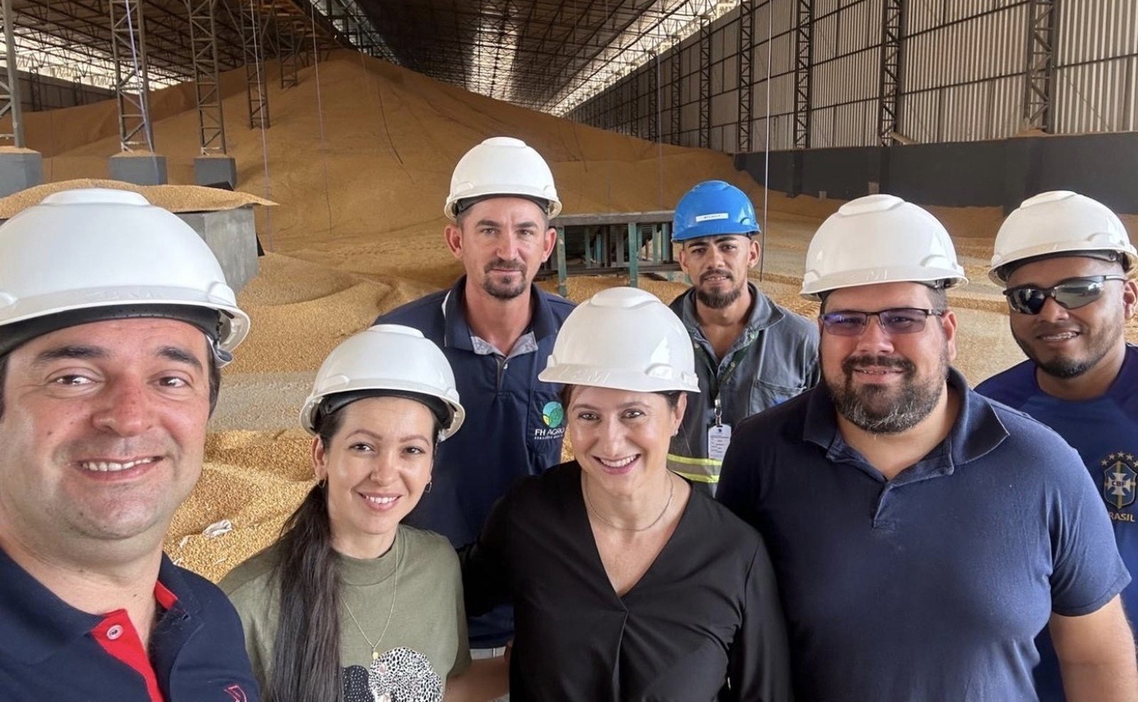 Grupo com capacetes de proteção em ambiente de armazenagem de grãos.